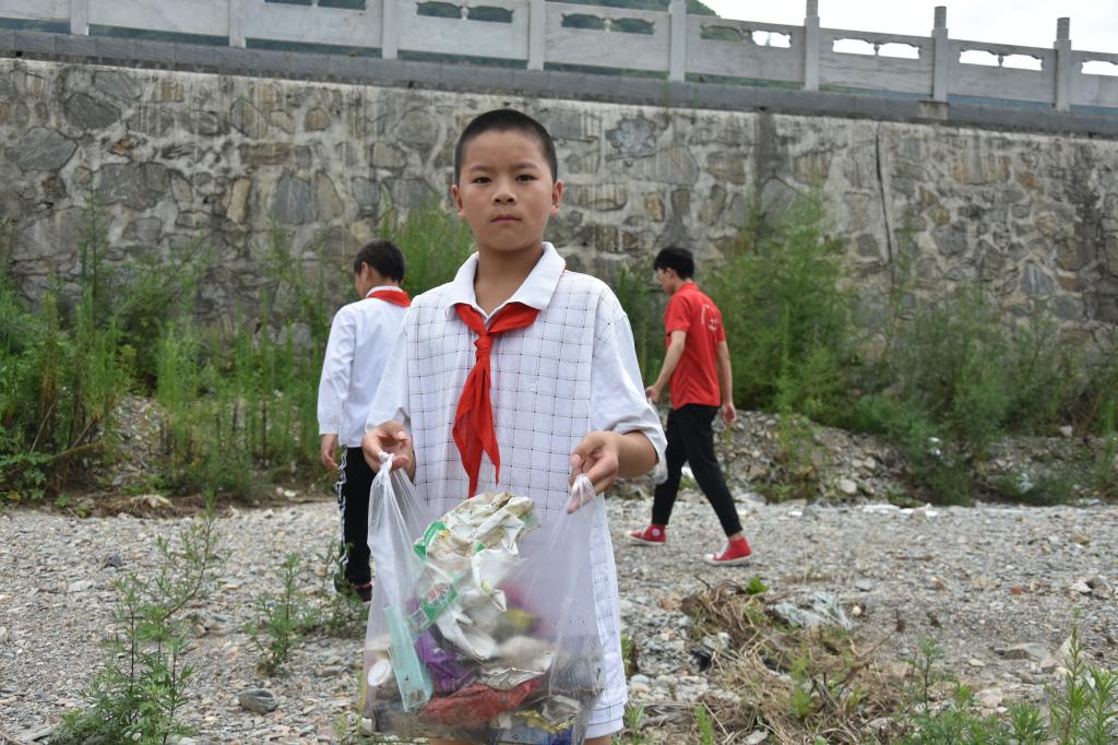 凤凰镇中心小学学生与我院“三下乡”志愿者共同捡拾河道垃圾